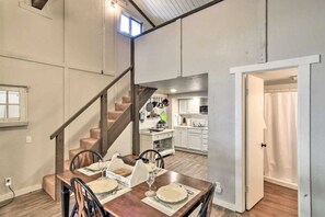 Enjoy meals in this stylish dining area with a high ceiling and exposed beams, featuring a dining table set with fine china and silverware.