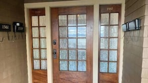 Une porte d’entrée en bois avec des panneaux de verre dépoli et une boîte aux lettres fixée au mur.