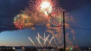 A fireworks display over a residential area with houses and a clear sky.
