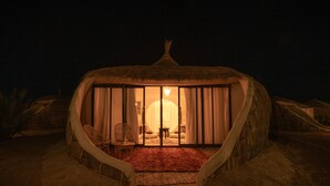 A thatched-roof structure with a circular window and a red carpet leading to the entrance. - Imperial Glory Lodges (Rissani)