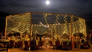 An outdoor dining area with string lights and a clear view of the moon. - Imperial Glory Lodges (Rissani)