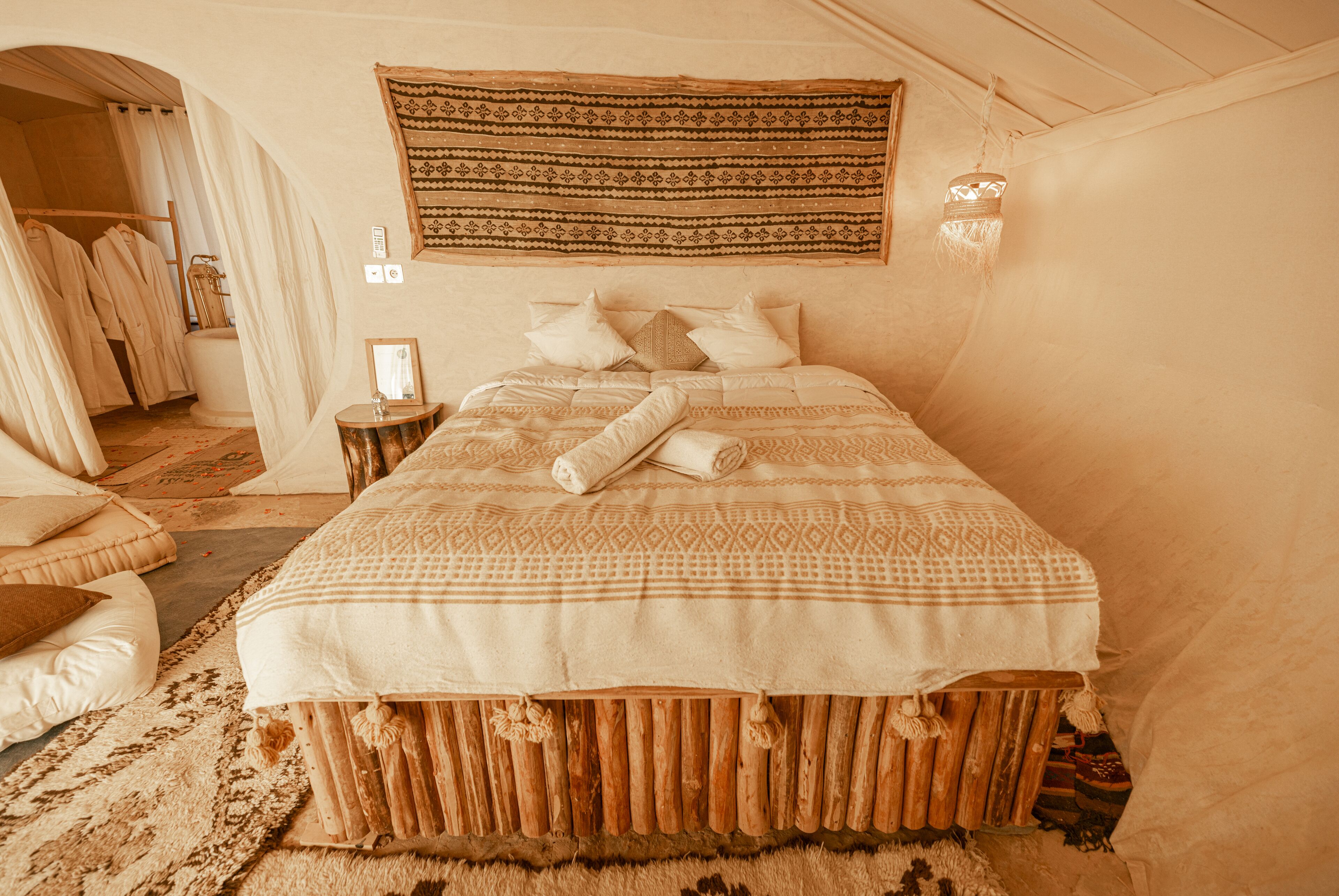 A cozy, well-appointed bedroom with a large bed, a wooden headboard, and a hanging tapestry.