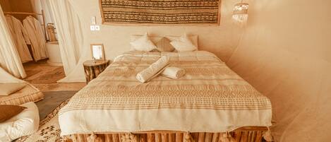 A cozy, well-appointed bedroom with a large bed, a wooden headboard, and a hanging tapestry.