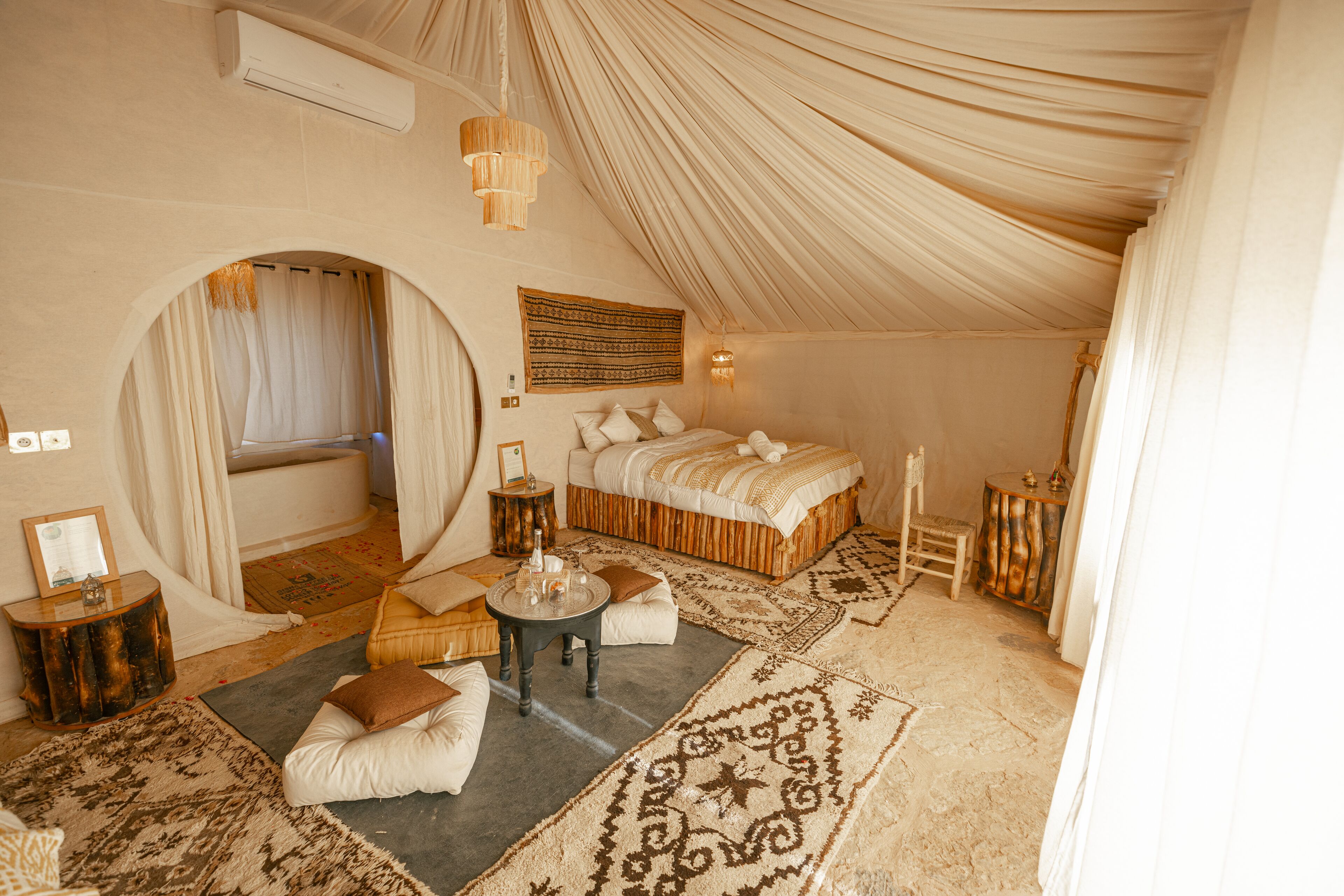 A tented room with a bed, a round table, and a chair.
