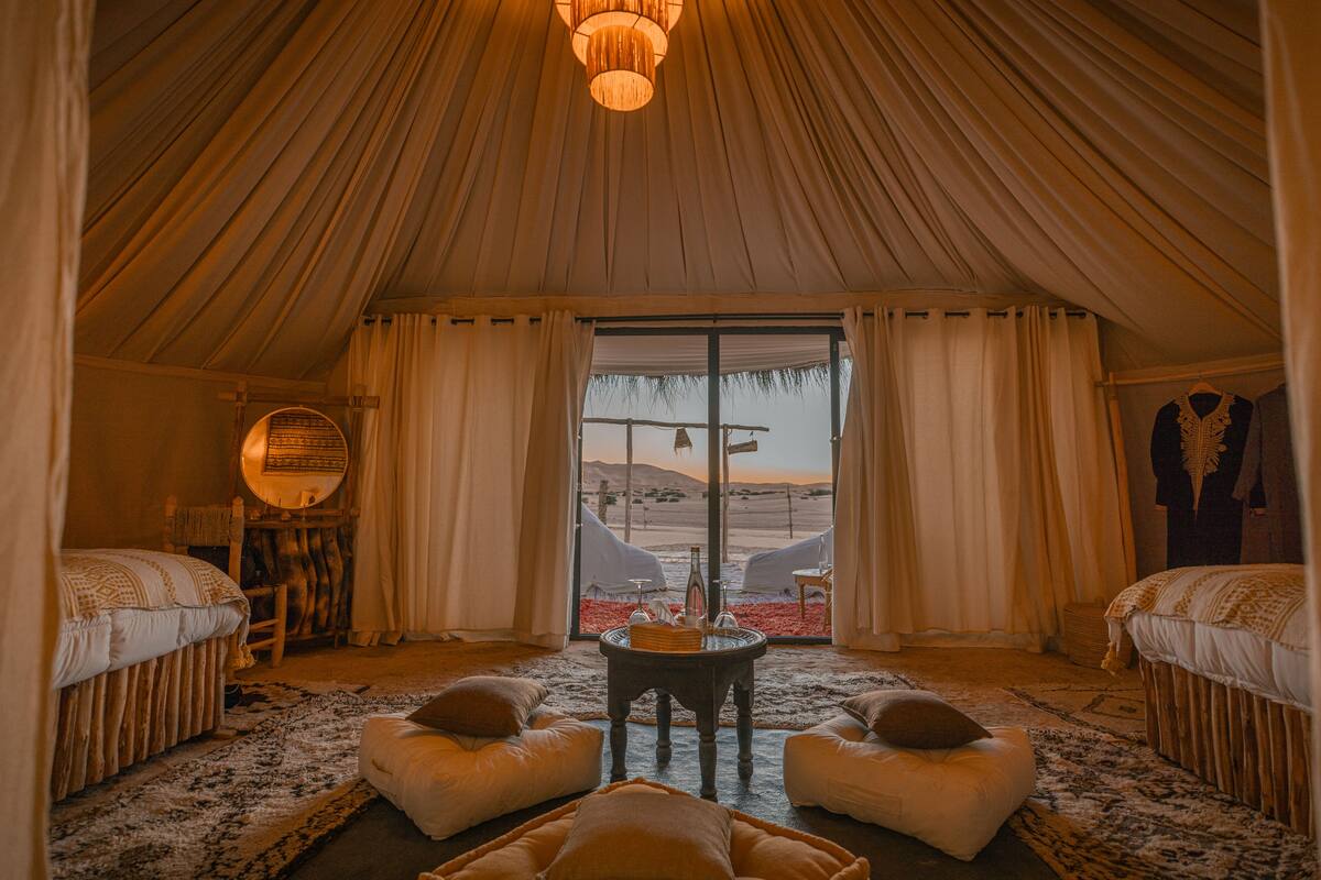 Una habitación con carpa, dos camas, una mesa redonda y vista al desierto.