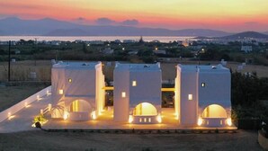 Um edifício moderno com três torres, cada uma com uma janela circular, ao pôr do sol.