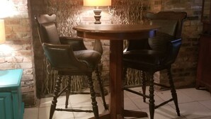 Un comedor con una mesa redonda y cuatro sillas, una lámpara y un equipo de aire acondicionado sobre una pared de ladrillo.