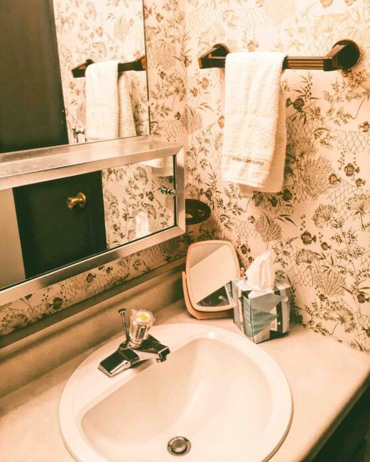 Un baño con lavamanos, espejo y perchero para toallas.