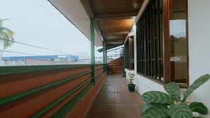 A covered corridor with a tiled floor, green railings, and a potted plant. - Quepos Inn (Quepos)