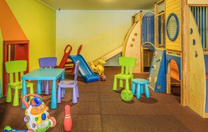 Ein Spielzimmer für Kinder mit Rutsche, Kletternetz und verschiedenen Spielzeugen.
