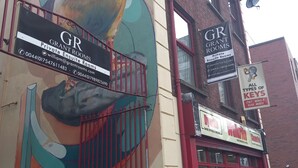Un edificio con un mural de un pájaro y un letrero que dice 'GRANT ROOMS Private En-suite Rooms'.