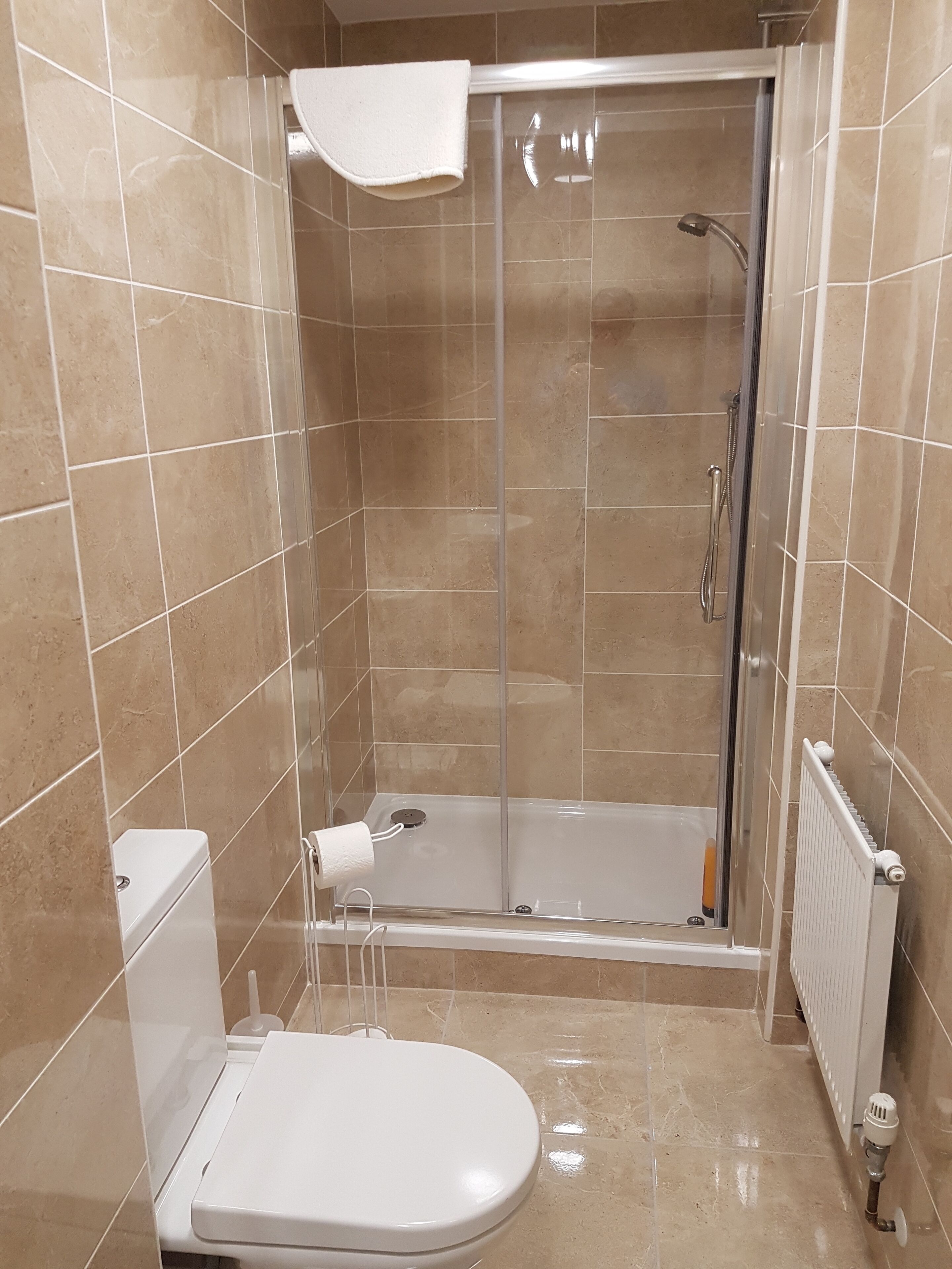 A bathroom with a shower, toilet, and a towel rack.