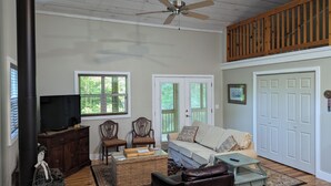 Un salon chaleureux avec une cheminée, des sièges confortables et un ventilateur de plafond.