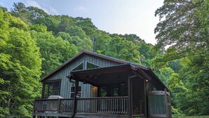 Un chalet rustique doté d’une terrasse en bois, entouré d’une forêt dense.