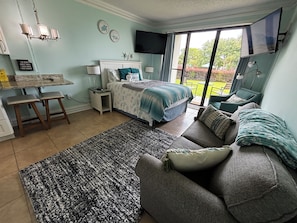 A bedroom with a bed, a sofa, a small table, and a TV.