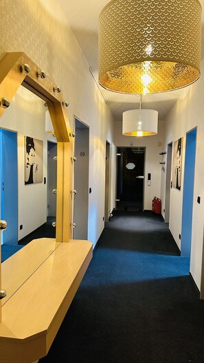 A hallway with a wooden vanity, a large mirror, and a hanging light fixture. - smart&beautiful Express (Nordkirchen)