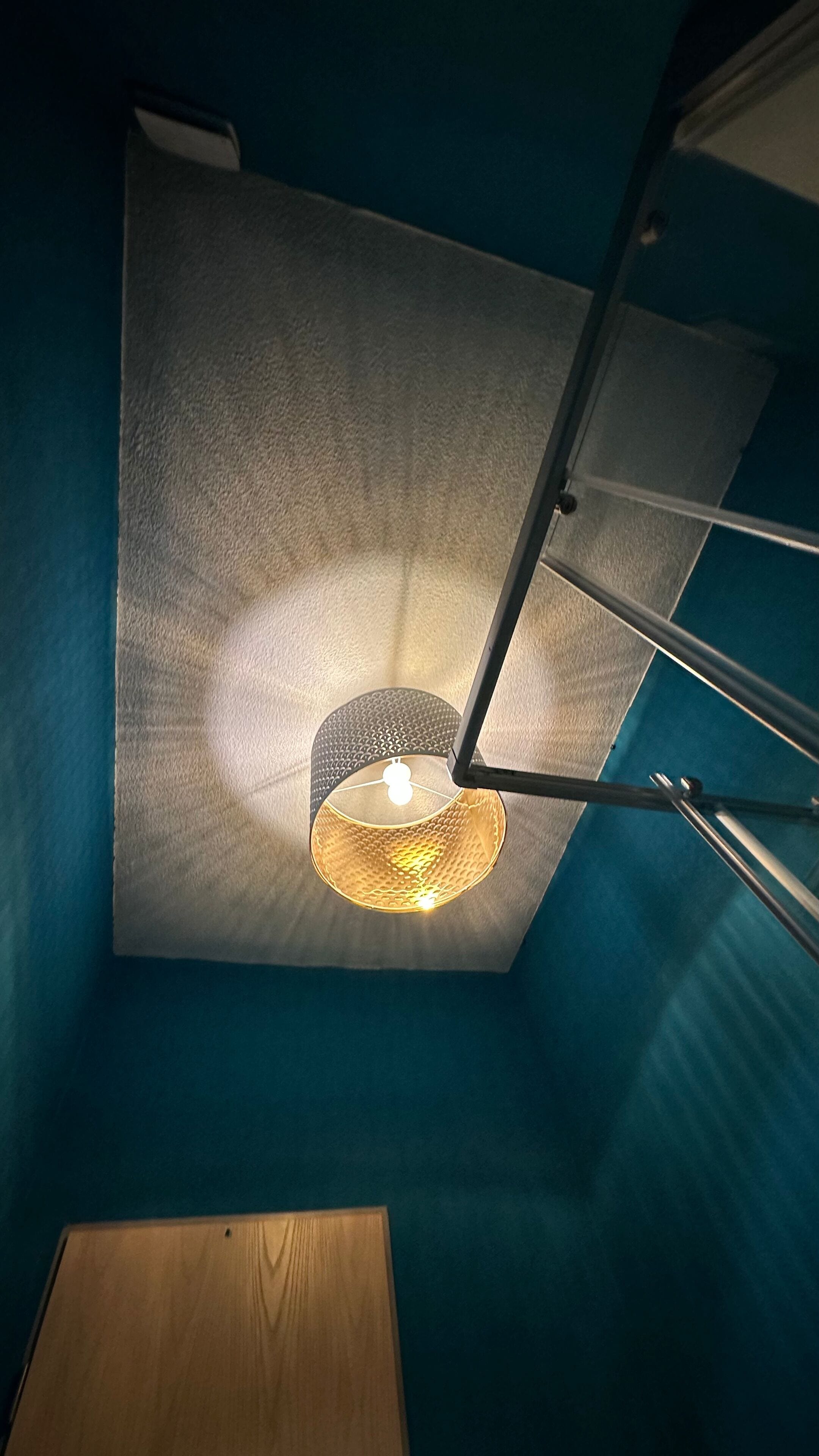 Un plafond agrémenté d’un luminaire à texture et de rampes en métal.
