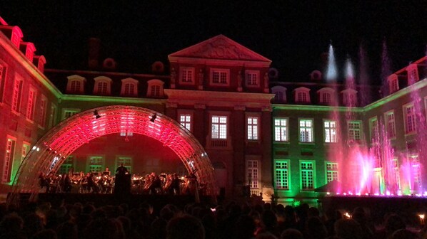 Un gran edificio con un escenario y zona para el público, que presenta una estructura de arco destacada con iluminación roja.
