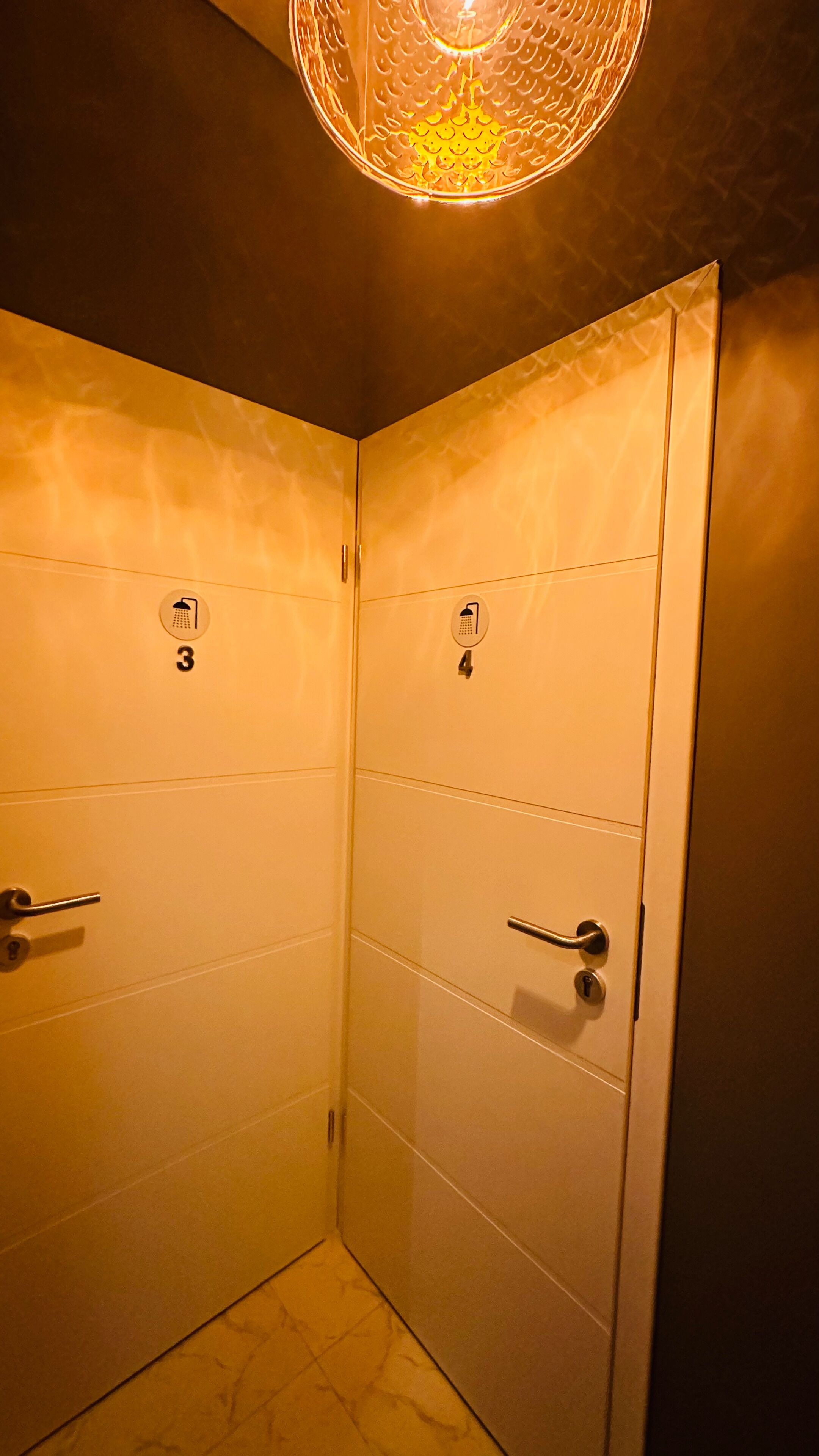 Un baño con dos cabinas de ducha, cada una identificada con un número y un icono de ducha.