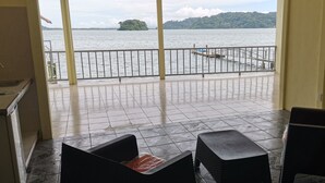 A balcony with a view of a lake and an island. There are two black chairs and a small table on the balcony floor. - Luxury apartment, on the waterfront (Golfito)