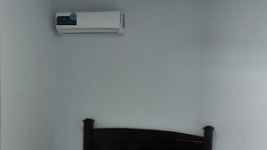 A bedroom with a bed, a wall-mounted air conditioner, and a small bedside table. - Luxury apartment, on the waterfront (Golfito)
