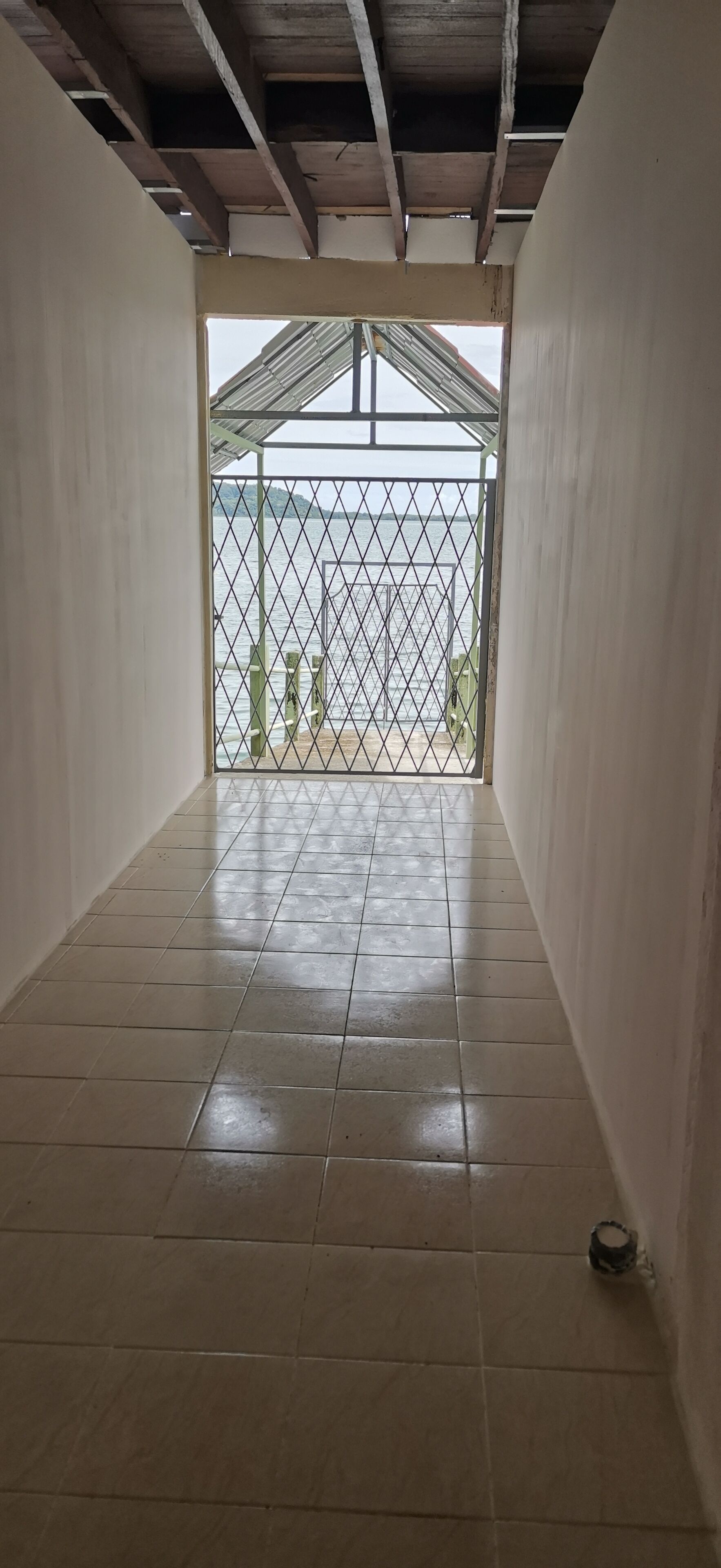 Ein Korridor mit Fliesenboden, der zu einem befestigten Bereich mit Blick aufs Meer führt.