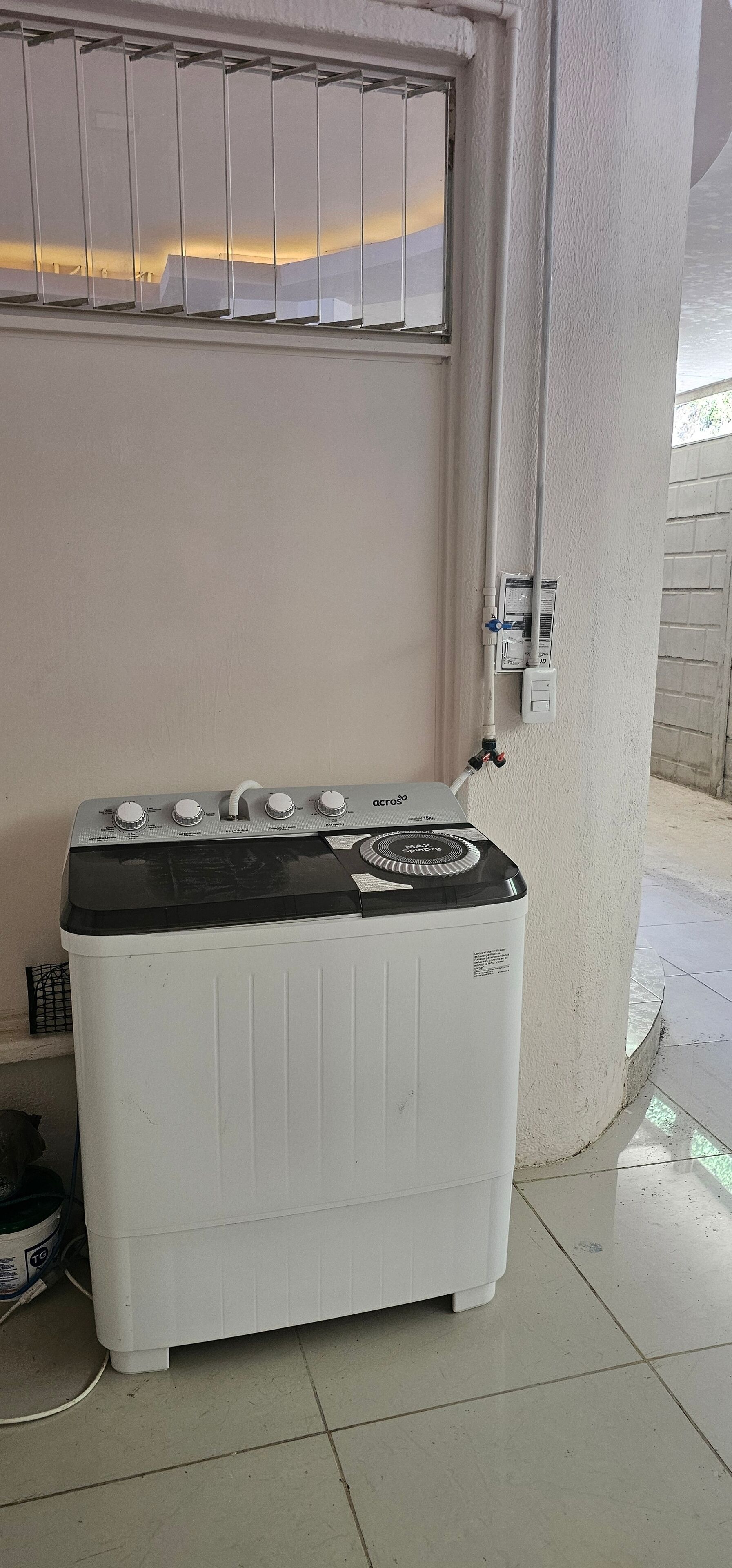 A white washing machine with a black top, located near a window with a view of the sunset.