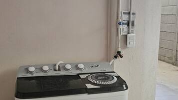 A white washing machine with a black top, located near a window with a view of the sunset.