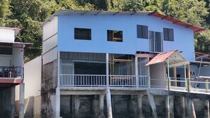 A two-story building with a balcony, a red roof, and a view of the surrounding area. - Luxury apartment, on the waterfront (Golfito)