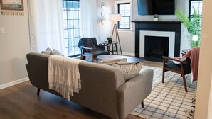 Ein Wohnzimmer mit einer Couch, einem Sessel und einem Kamin.