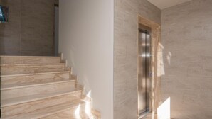 Un intérieur moderne avec un escalier en marbre et un ascenseur fixé au mur.