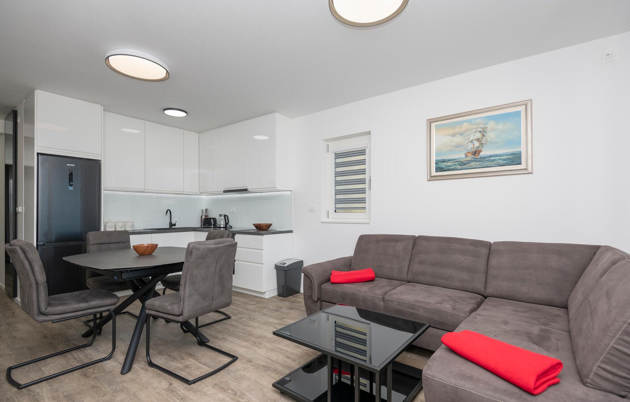 Un salon moderne avec un canapé gris, une table basse et un coin repas comprenant une table et des chaises.