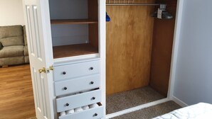 Un vestidor con puertas abiertas, una estantería de madera y una barra para colgar.