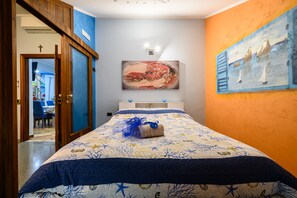 Ein Schlafzimmer mit einem Bett, einem Gemälde und einer Tür zu einem anderen Raum.