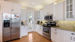 Una cocina con gabinetes blancos, electrodomésticos de acero inoxidable y piso de madera.
