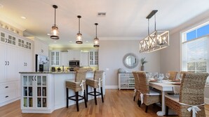 Una cocina amplia con armarios blancos, una isla central y lámparas colgantes.