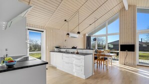 Een moderne keuken met een groot kookeiland, witte kasten en een eethoek met houten stoelen.