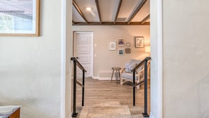 A hallway with a wooden floor, a white door at the end, and a staircase with a handrail. - The Pelican Point (St. Augustine)