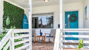 A welcoming entrance with a number '24' sign, a blue door with a wreath, and a patio area with chairs and a table. - The Pelican Point (St. Augustine)