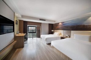 Ein Hotelzimmer mit zwei Betten, einem Fernseher, einem Schreibtisch und einem Balkon.