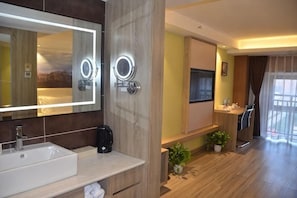 Un baño moderno con un espejo grande, un lavabo y una cafetera.
