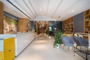 A reception area with a counter, seating, and a bookshelf. - Miya Hotel (Chongqing Jieshi Xinke) (Chongqing)