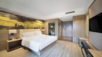 A modern hotel room with a large bed, bedside tables, a flat-screen TV, and a mural on the wall.