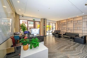 A reception area with a reception desk, seating area, and a large bookshelf. - Quanzi Art Inn (Shenzhen)