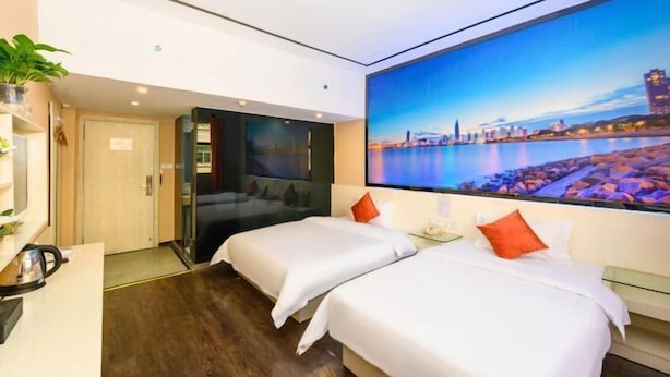 A hotel room with two beds, a large cityscape painting on the wall, a desk with a kettle, and a door leading to another room. - Quanzi Art Inn (Shenzhen)