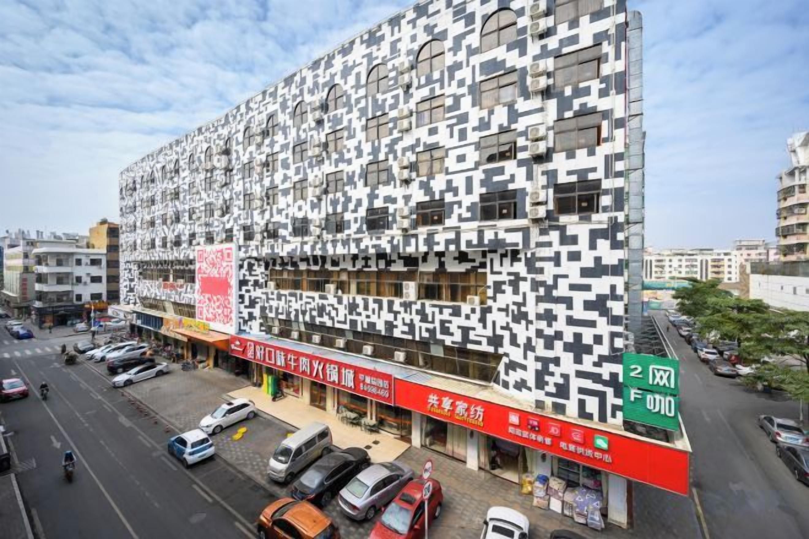A modern building with a unique facade, located at an intersection with visible signage for a business.