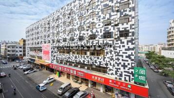 A modern building with a unique facade, located at an intersection with visible signage for a business.