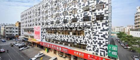 A modern building with a unique facade, located at an intersection with visible signage for a business.