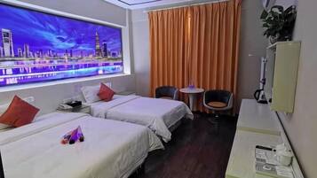 A hotel room with two beds, a window with a cityscape view, a desk with a chair, and a small table with a plant.