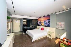 A modern hotel room with a large bed, a desk, a chair, a TV, and a painting on the wall. - Quanzi Art Inn (Shenzhen)
